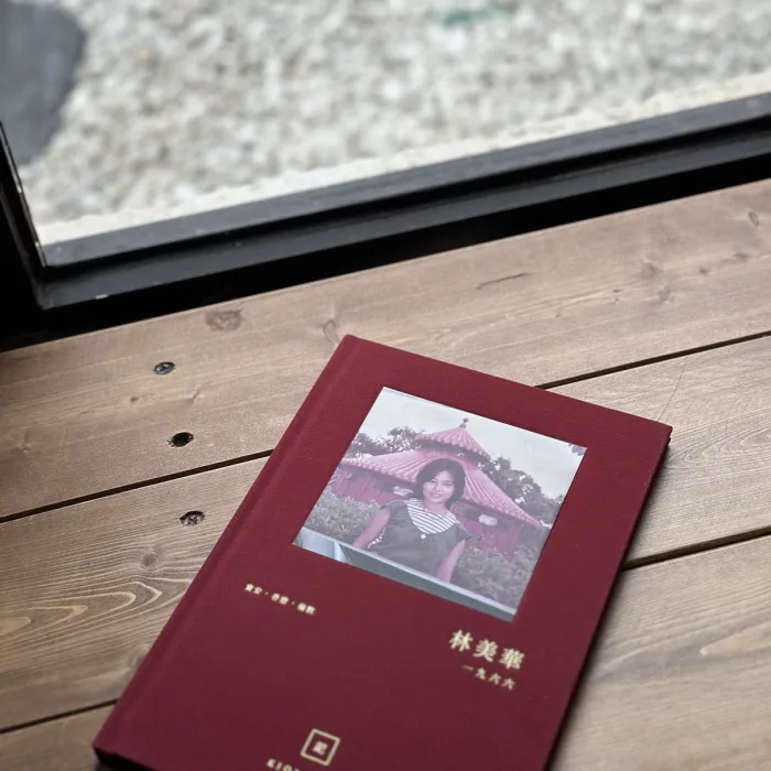 紅色布面燙金長輩故事書封面,內嵌長輩後生時嘅舊相同金色姓名年份
